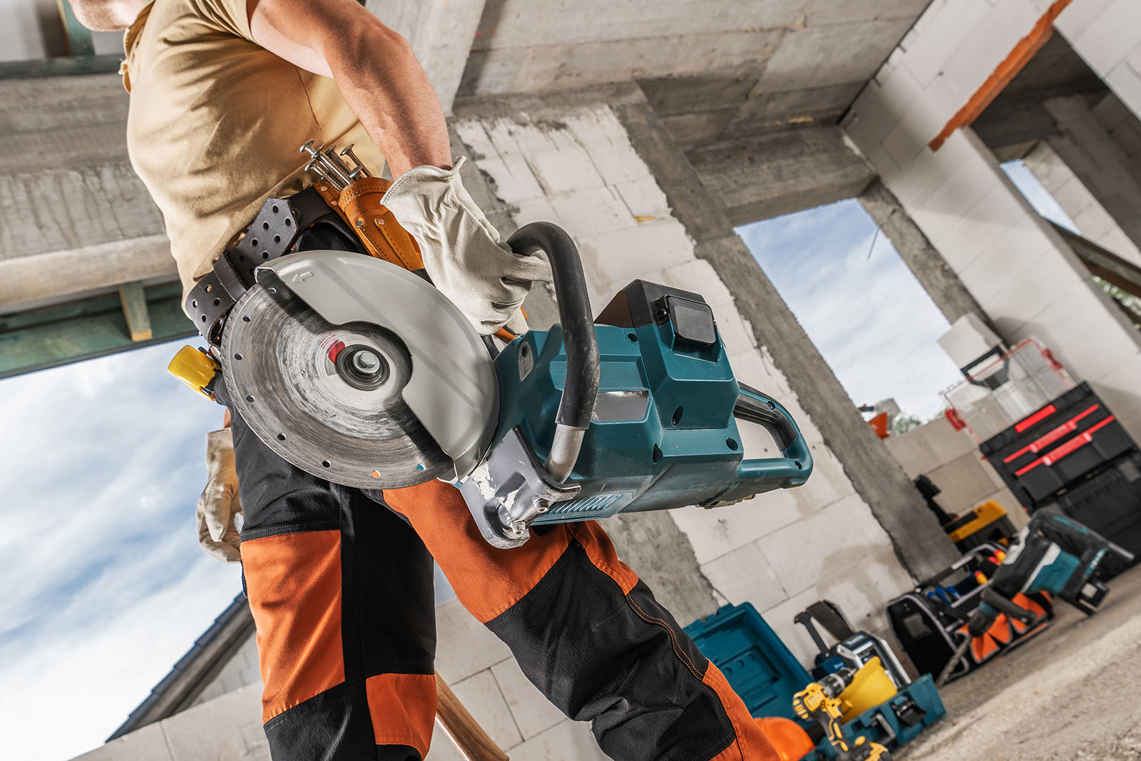 A man walking with a circular saw through a job site.
